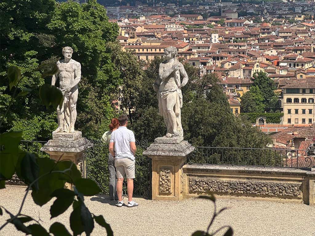 Two classical statues in Bardini Gardens with panoramic views of Florence’s rooftops and historic center