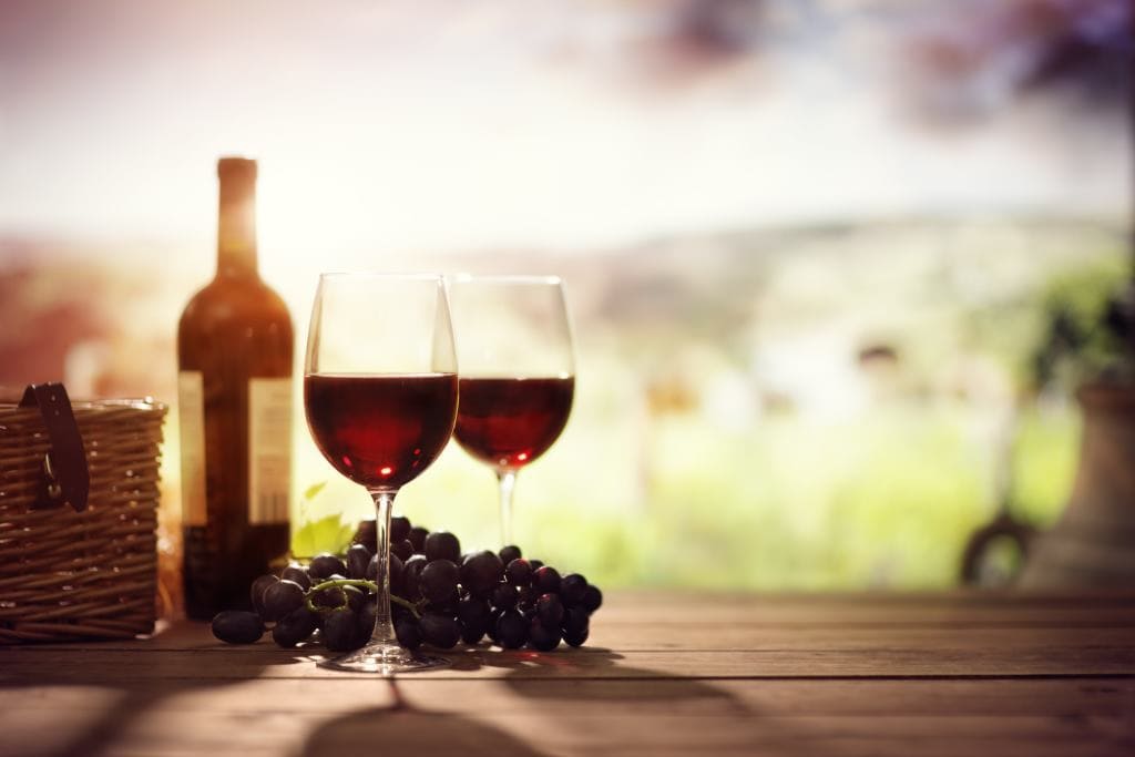 red-wine-bottle-and-glass-on-table-in-vineyard
