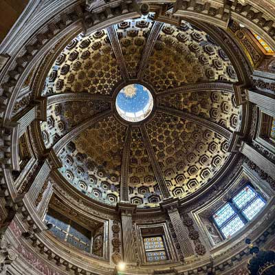 Intricate dome ceiling of Siena Cathedral featuring geometric patterns, golden accents, and central oculus