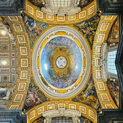 Ornate fresco and architectural details on the ceiling of St. Peter’s Basilica in Vatican City, with golden frames and religious imagery.