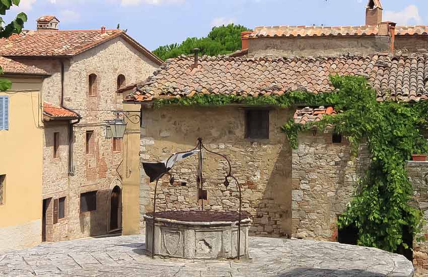 Ancient stone well in Castiglione d'Orcia surrounded by rustic buildings in Tuscany, Italy