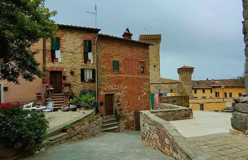 Charming medieval street with stone houses and towers in Lucignano, Tuscany