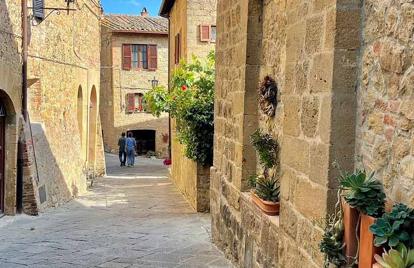 Stone alleyway in Monticchiello, Tuscany, with potted plants and rustic homes
