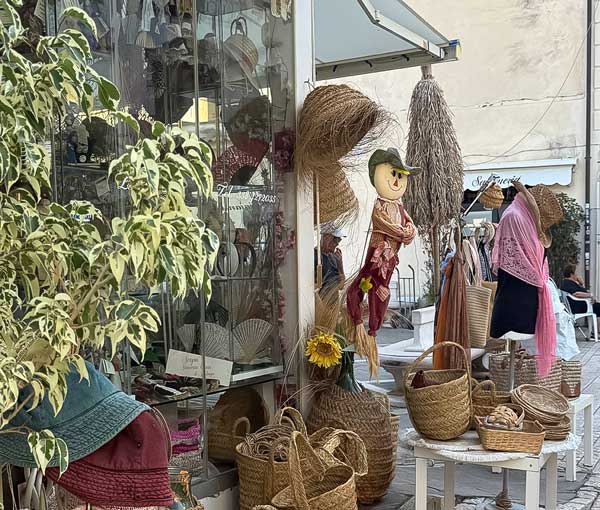 Handmade straw baskets and woven crafts displayed outside a local artisan shop in Sperlonga, Italy.