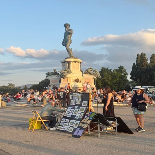 Bronze statue of David at Piazzale Michelangelo in Florence with tourists at sunset